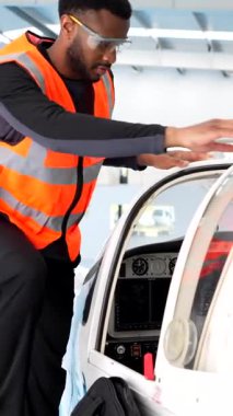 Yüksek görüş mesafesi olan uçak mühendisi küçük uçağın kokpitine tırmanıyor, profesyonel hassasiyetle uçuş öncesi teftiş yapıyor.