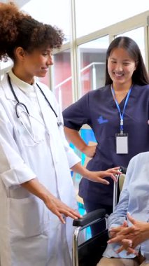 Sağlık uzmanları, tekerlekli sandalyedeki yaşlı bir kadına olumlu ve güven verici bir ortam yaratarak bakımı ve desteği sağlıyorlar.