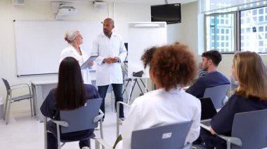 Tıp uzmanları ilgili öğrencilerle dolu bir sınıf ortamında ilgi çekici bir eğitim seansı düzenliyorlar. Eğitim atmosferi ve aktif katılım
