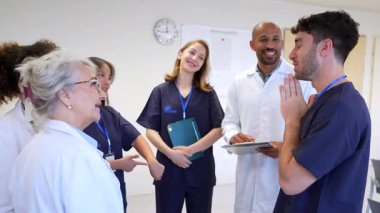 Tıbbi ekip yeni stajyeri sıcak bir şekilde karşılıyor. Profesyonel dönüm noktasını el sıkışma, gülümseme ve parlak hastane ortamında destekleyici jestlerle kutluyorlar.