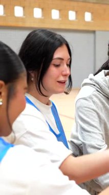 Kadın basketbolcular sıkı bir şekilde el ele tutuşuyor, takım ruhunu somutlaştırıyor ve zor kazanılan zaferi kapalı sahada duygusal bir bağ kurarak kutluyorlar.