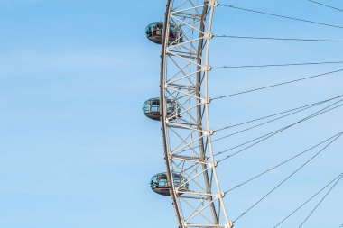 Cam kapsüller, açık mavi gökyüzüne karşı Londra göz dönme dolabında yavaşça dönüyor. Şehrin nefes kesici panoramik manzarasını sunuyorlar.
