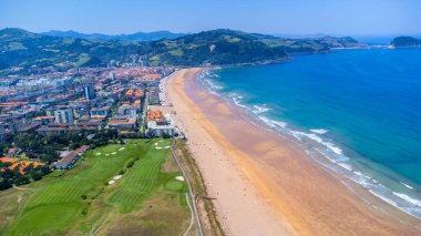 Güneşli bir yaz gününde Zarautz, Gipuzkoa 'nın havadan görünüşü, altın kumları, turkuaz suları ve Bask ülkesinin yeşil tepelerini gösteriyor.