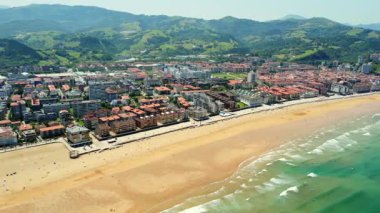 Güneşli bir yaz gününde Gipuzkoa, Bask, İspanya 'daki Zarautz kasabasının, plajın ve okyanus dalgalarının hava manzarası.
