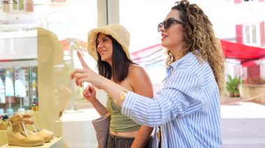 Fashion influencers collaborating, presenting newest summer footwear collection through engaging interaction inside stylish boutique storefront window display