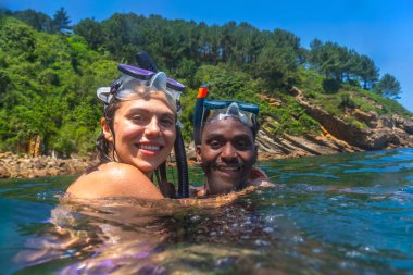Irklar arası çift şnorkelle yüzme macerasından zevk alıyor, manzaralı okyanus sularını kucaklıyor.