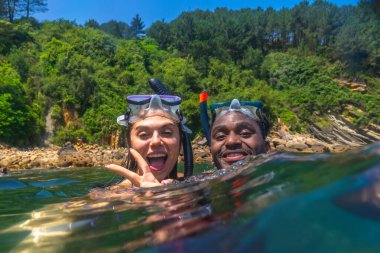 Irklar arası çift canlı okyanusta birlikte şnorkelle yüzüyor, yaz tatilinin tadını çıkarıyor ve neşeli anılar yaratıyorlar.