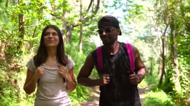 Çok ırklı yürüyüşçüler orman yolunda birlikte yürüyor, sohbet ediyor ve bereketli ormanlık araziyi keşfederken yaz güneşinin tadını çıkarıyorlar.