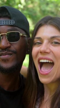 Genç, çok ırklı bir çift parkta eğleniyor, gülümsüyor, gülüyor ve birlikte özel bir an paylaşıyorlar.