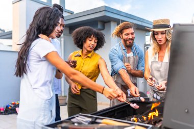 Neşeli arkadaşlar çatıdaki bir partide barbekü ızgarasında şiş üstünde lokum kızartıyorlar.