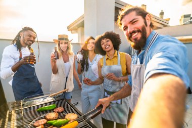 Neşeli arkadaşlar çatıdaki barbekü partisinden, ızgara yemekten, içeceklerden ve selfie çekmekten zevk alıyorlar.
