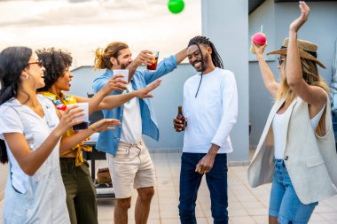 Neşeli genç insanlar neşeli bir çatı partisinde eğleniyor ve neşeyle dans ediyor. Gün batımının altında unutulmaz anılar yaratıyorlar.