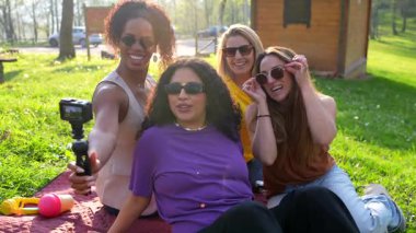 Güneşli bir günün tadını çıkarırken grup selfie 'sini çeken gülen bayan arkadaşlar, yemyeşil park ortamında unutulmaz bir an yaratıyorlar.