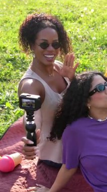 Çeşitli bayan arkadaşlar neşeli anları yakalar, kahkahalarını paylaşır ve güneşli bir günde çimenli park manzarasında eğlenceli selfie çekerken anılar yaratır.