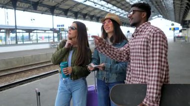 Turistler haritaya danışıyor ve tren istasyonundaki seyahat planlarını tartışıyor, maceraya hazır.