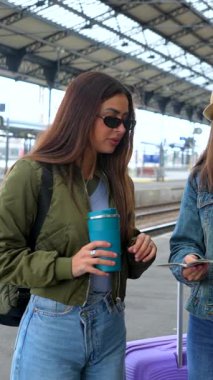 Kalabalık tren istasyonunda toplanan turistler, seyahat belgelerini ve biletleri karşılaştırırken yaklaşan yolculuk için heyecanı paylaşıyorlar.