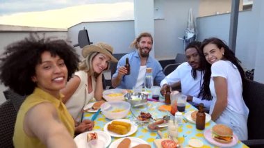 Çeşitli arkadaş grupları çatıdaki yaz akşamı toplanmalarında ızgara yaparken ve selfie çekerken neşeli anları yakalıyorlar.