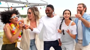 Çok kültürlü arkadaşlar şarkı söylerken, dans ederken ve renkli ışıklar altında, yazın çatıda eğlenirken unutulmaz anlar yaratıyorlar.