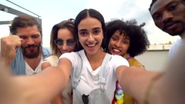 Bir grup neşeli çoklu etnik arkadaş çatıdaki bir partide selfie çekiyor ve birlikte vakit geçiriyorlar.