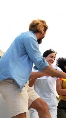 Neşeli çoklu etnik arkadaşlar dans edip içiyorlar, beyaz arka planda kapalı çatı partisinin tadını çıkarıyorlar.