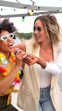 Arkadaşlar canlı çatı partisinde karaoke yapıp dans ediyorlar, canlı çeşitlilik sergiliyorlar ve kentsel sosyal toplantının neşesini paylaşıyorlar.