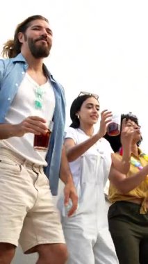 Coşkulu çoklu etnik arkadaşlar dans ederken, içki içerken ve heyecan içerken şehrin arka planında yer alan kutlamalar sırasında