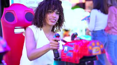 Lunaparkta yarış oyunu oynayan genç bir kadın. Konsantre heyecan gösterirken atari salonu simülatörüne bağlanıyor. Canlı bir eğlence deneyimi yaşıyor.