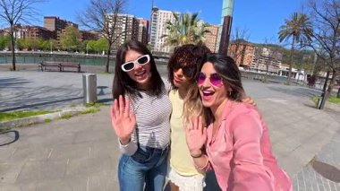 Birlikte yürüyen güneş gözlüğü takan şehirli kızlar yaz şehri macerası boyunca mutluluk saçıyorlar, neşeli arkadaşlık anlarını paylaşıyorlar.