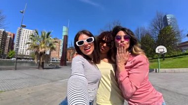 Neşeli bayan arkadaşlar yaz anılarını yakalıyorlar. Resimli Bilbao kentsel manzarasına karşı grup selfie çekiyorlar. Boş zamanlarında neşe ve dostluk yayıyorlar.