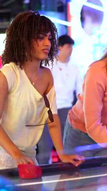 Havalı hokey oynarken yarışan ve gülen bayan arkadaşlar renkli oyun salonlarında hareketli oyun heyecanıyla enerjik boş vakitlerin tadını çıkarıyorlar.