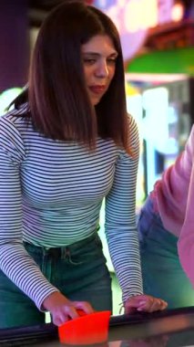 Genç kadınlar neşeli bir şekilde hava hokeyi maçına katılıyor, canlı renklerin ve hareketli eğlence oyun merkezinin içindeki enerjik atmosferin tadını çıkarıyorlar.