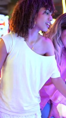 Neşeli genç kadınlar birlikte eğleniyorlar, hareketli bir eğlence mekanında atari oyunları oynuyorlar.