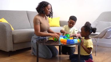 Aile üyeleri renkli bloklarla birlikte oynuyor ve inşa ediyor, çocuk gelişimi ve yaratıcılığı sıcak oturma odasında teşvik ediyor