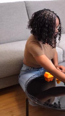 Anne ve çocuklar oyun zamanının tadını çıkarıyorlar. Oturma odasındaki bir masada renkli bloklar inşa ediyorlar.