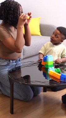 Anne ve çocuklar birlikte güzel vakit geçiriyorlar. Oturma odalarında renkli bloklar yapıp oynuyorlar.