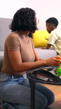 Aile bireyleri birbirine kenetlenmiş canlı yapı taşlarıyla meşgul, yaratıcı oyun ve kaynaşma anlarını rahat oturma odasında paylaşıyorlar.