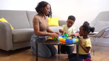 Aile üyeleri renkli bloklarla birlikte oynuyor ve inşa ediyor, çocuk gelişimi ve yaratıcılığı sıcak oturma odasında teşvik ediyor