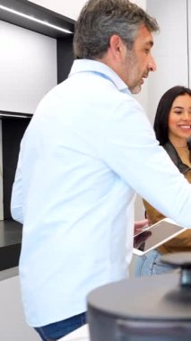 İç mimari profesyonel rehber mutfak tezgahı seçim süreci boyunca genç çifte yol gösterici, tablet ile malzeme seçenekleri keşfetmek şık sergi ortamında