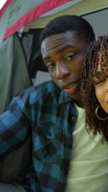 Genç siyahi çift kamp gezisi sırasında selfie çekerken ve çadırda komik suratlar yaparken eğleniyor.