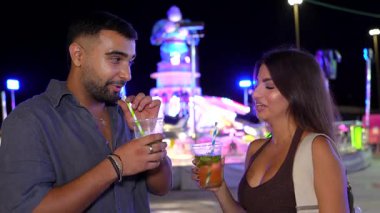 Genç yetişkinler samimi anları paylaşıyor, renkli karnaval ışıkları altında kokteyller içiyor, romantik yaz gecelerinde neşe saçıyor ve iletişim kuruyorlar.