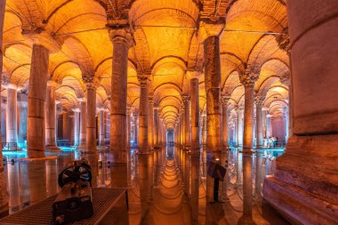 İstanbul 'daki antik bazilika sarnıçlarının su yüzeyine yansıyan görkemli sütunları ve kemerleri aydınlatan ılık turuncu ışık, hindi