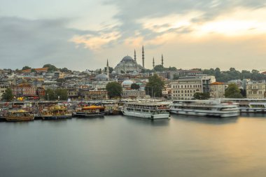 Güneşin batışında altın boynuzda yüzen feribotlar İstanbul siluetine hükmeden görkemli Süleyman Camii 'nin manzaralı bir şehir manzarası yaratmasıyla