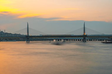 İstanbul, Türkiye 'deki Golden Horn metro köprüsünü geçen bir metro treni gün batımında uzun süre görüntülendi.