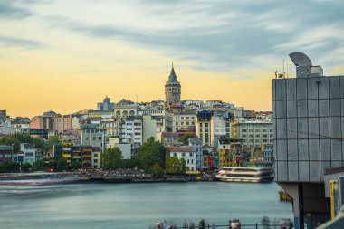 Galata Kulesi, İstanbul 'daki altın boynuz boyunca renkli binaların üzerinden yükseliyor. Canlı bir günbatımında.