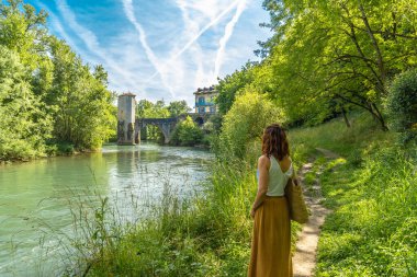 Fransız kırsalında yaz tatilinin tadını çıkaran bir kadın ortaçağ köprüsüne ve Pirenes Atlantik 'teki sauveterre de bear kulesine hayran.