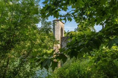 Yeşil yapraklar, Fransa 'nın Sauveterre de Bear kentindeki bir ortaçağ köprü kulesini çerçeveleyerek tarih ve doğa manzarası yaratıyor.