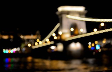 Bulanık ışıklar Budapeşte 'deki zincir köprüyü aydınlatıyor, geceleri Hungary, Tuna Nehri' ni yansıtıyor, büyülü bir atmosfer yaratıyor.