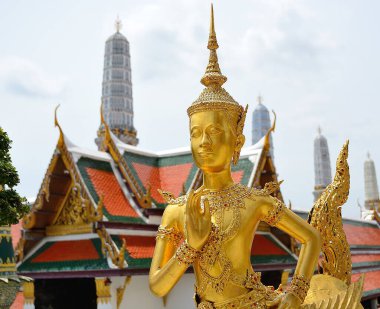 Altın Kinnara heykeli, Tayland 'ın Bangkok kentindeki Wat phra kaew tapınağı kompleksinin içinde geleneksel bir Thai selamı ile el ele dua ediyor.
