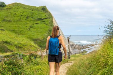 Sakoneta sahiline doğru yürüyen dişi turist sineklerin ve okyanusun manzarasının tadını çıkarıyor.