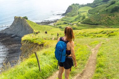 Sakoneta Sahili 'nin manzarasına ve Zumaia, Gipuzkoa, Bask Ülkesi' ndeki sahil sineğine hayran olan kadın yürüyüşçü.